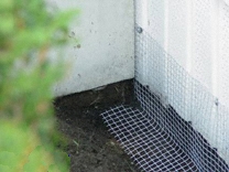 1/2- inch wire mesh secured to the base of a shed and buried several inches under ground with a 90- degree angle to prevent animals from accessing under the shed.  Use screws with fender washers to secure the mesh to the structure.